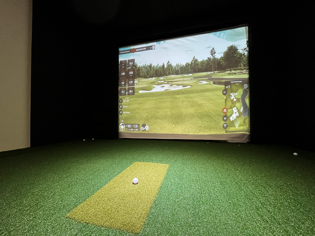 A golf simulator bay at Partee Golf, screen and putting turf